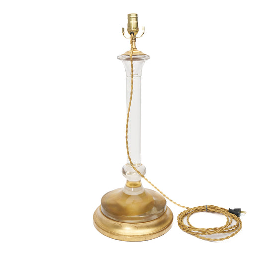 Glass table lamp with a gold base and clear glass shade on a white background