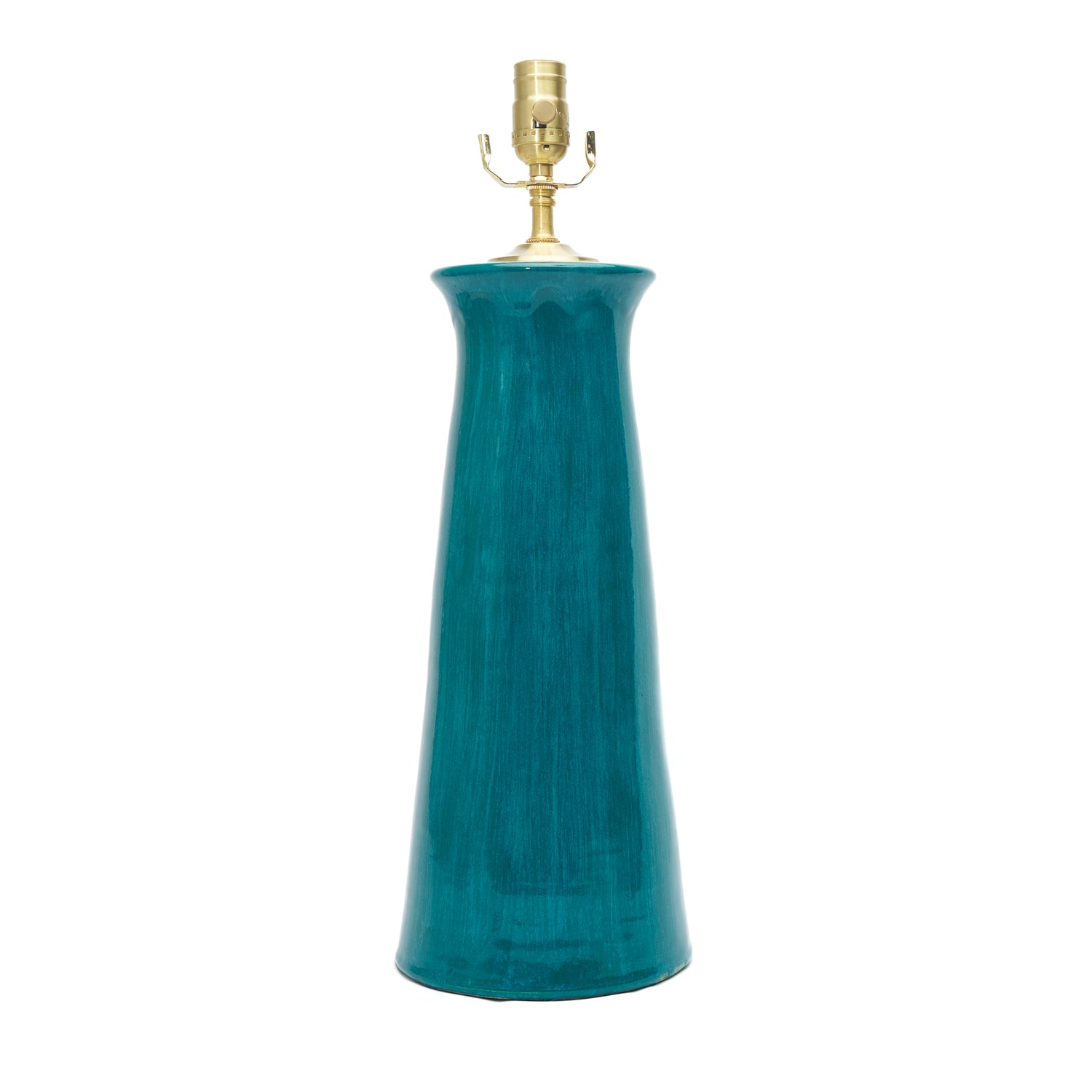 A tall, flared ceramic table lamp base in a glossy teal blue-green glaze, topped with a brass metal socket and shade, shown against a plain white background.