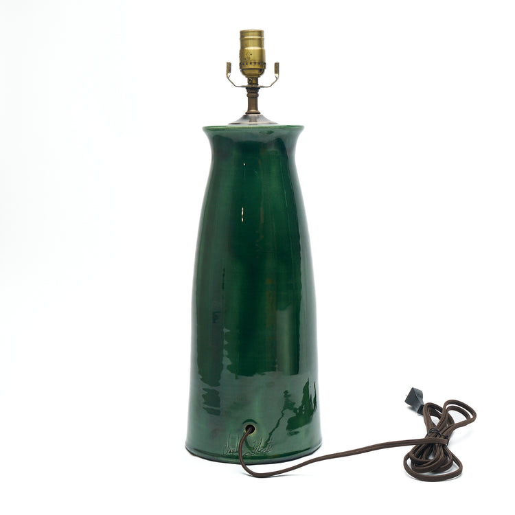 A dark green ceramic table lamp with a tapered base, a brass-colored metal socket at the top, and a dark brown power cord coiled on a white background.