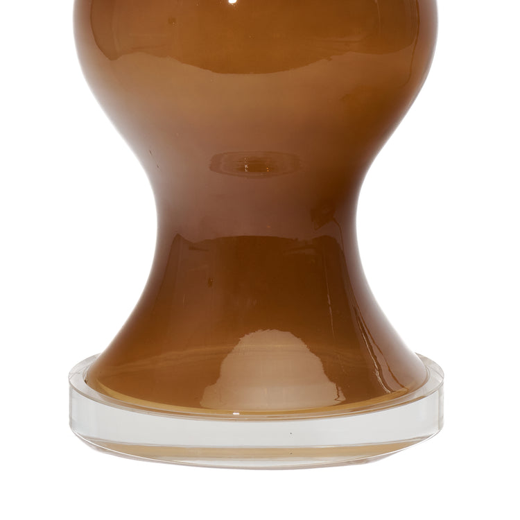 Close up of the base of a coffee brown lamp with a lucite base on a white 