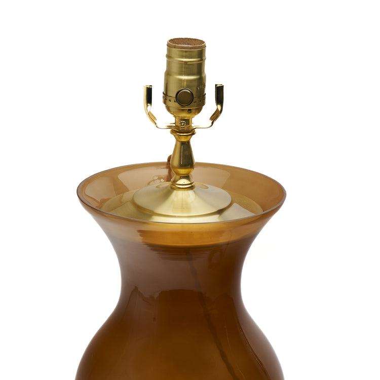 Close up of the top of a coffee brown lamp with a lucite base on a white background