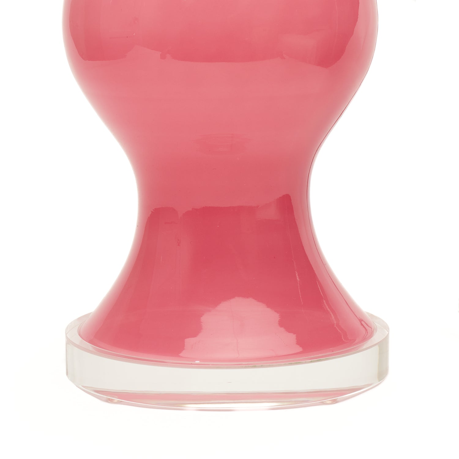A close-up of a pink conch glass lamp with a lucite circular base, photographed against a white background.