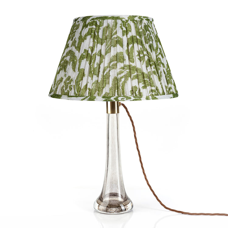 Table lamp with a green and white patterned shade on a white background