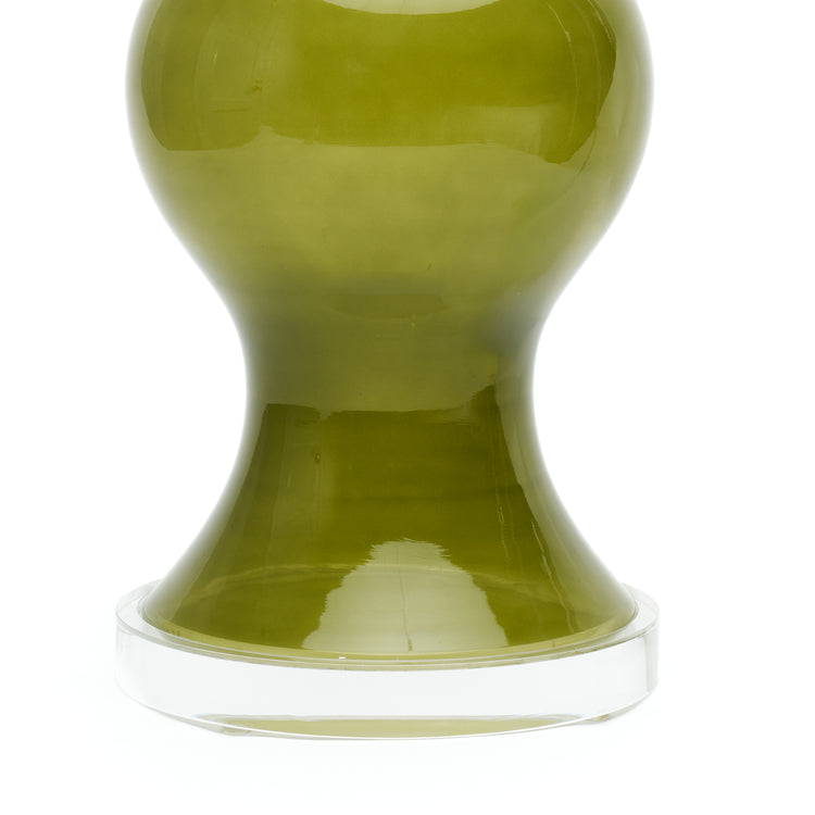A close-up of a green glass lamp with a  lucite circular base, photographed against a white background.