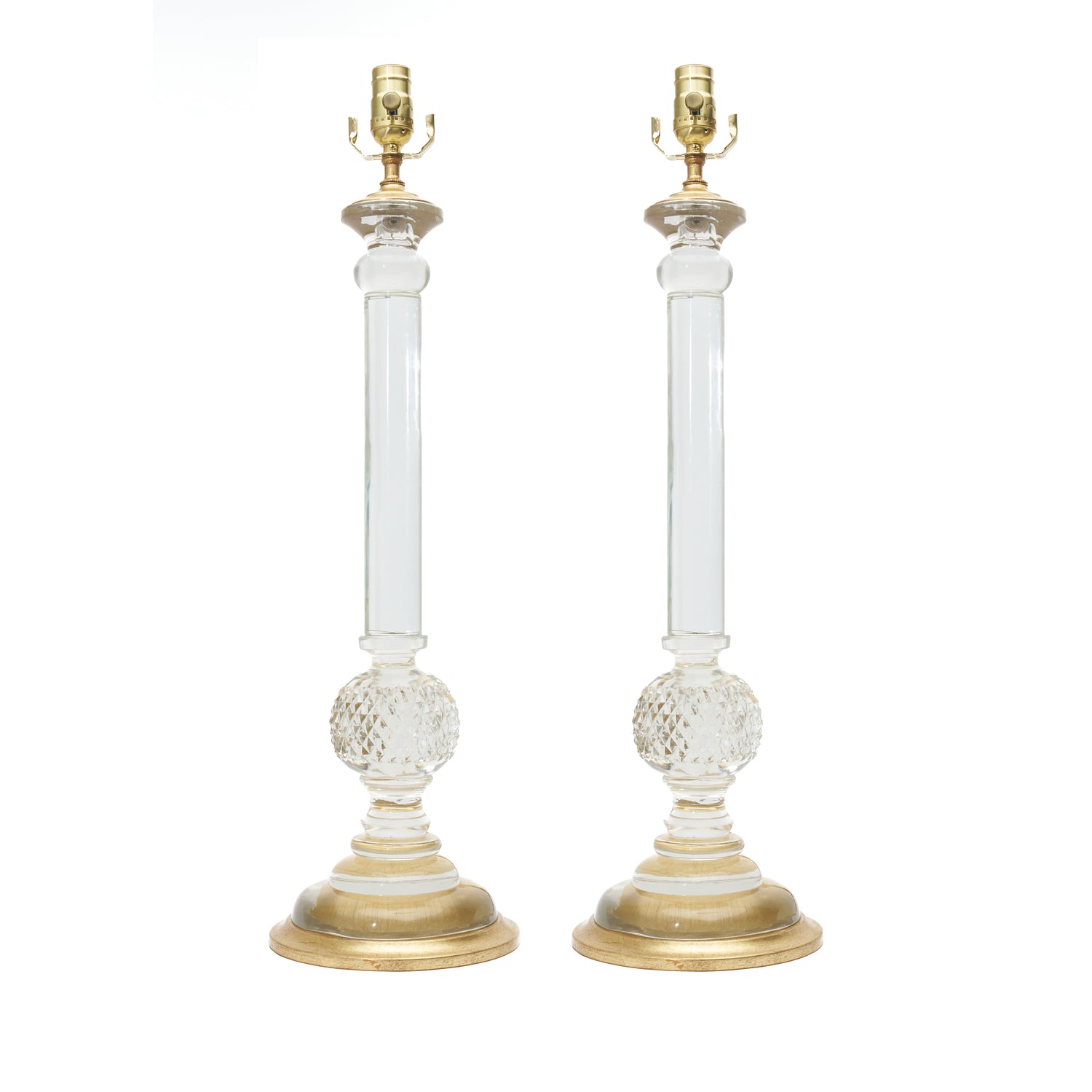 A pair of elegant table lamps with clear glass columns, textured lower globes, and polished gold-finished bases and lamp fittings, shown against a plain white background.