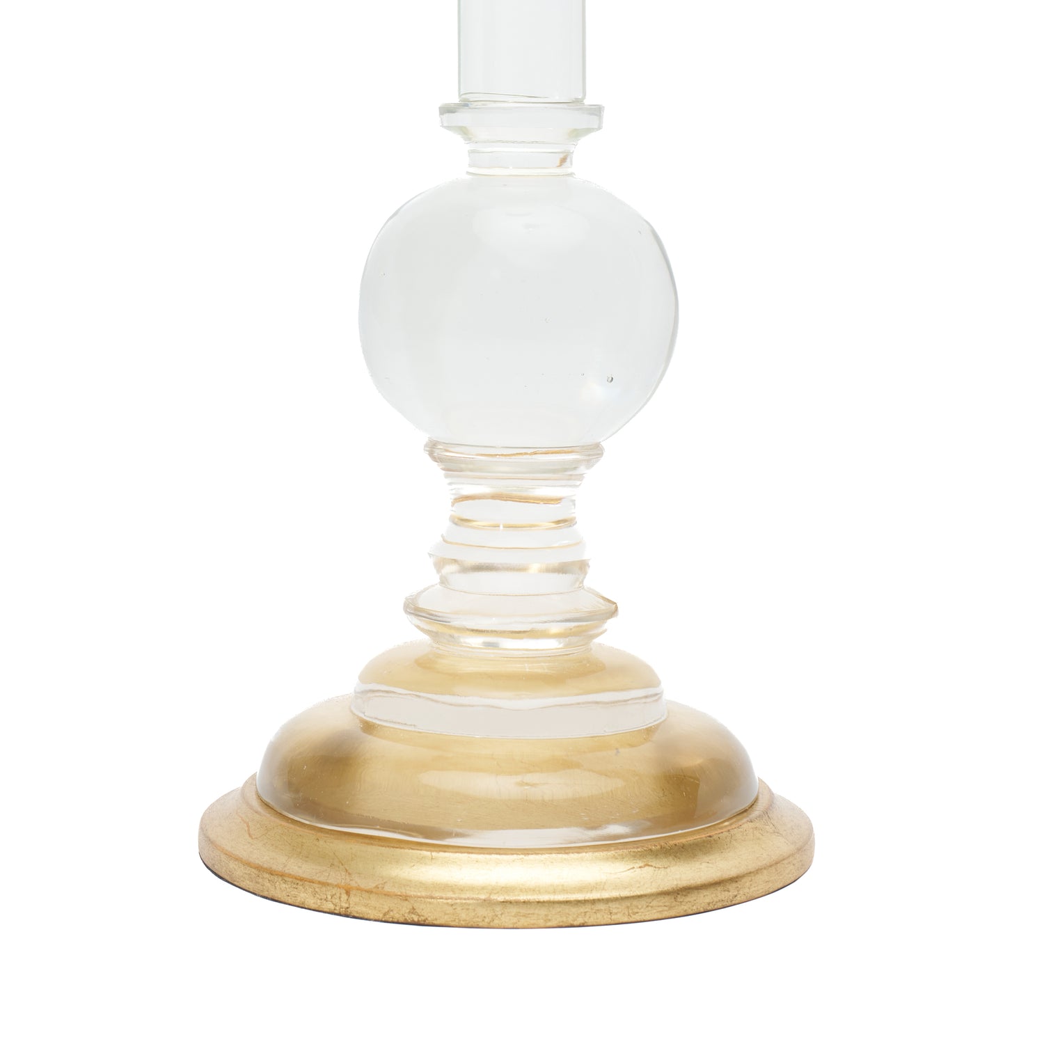 A close-up of a table lamp base, featuring a round gold-finished base and a clear glass stem, shown against a plain white background.